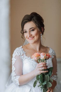 Bir kadın elinde bir buket çiçek tutuyor ve gülümsüyor. Görüntünün sıcak ve mutlu bir havası var.