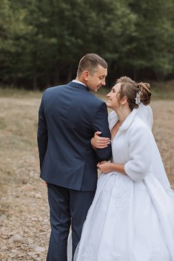 Bir gelin ve damat tarlada kameraya gülümsüyor. Gelin beyaz bir elbise ve beyaz bir şal giyer, damat ise mavi bir takım giyer. Sahne büyük ihtimalle bir düğün.