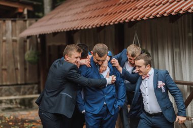 Takım elbiseli bir grup adam birbirlerine sarılıyorlar. Sahne sıcak ve dostane.