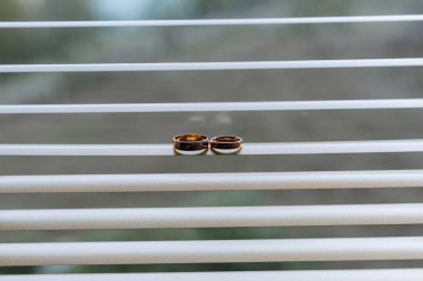 İki altın alyans pencere pervazında duruyor. Yüzükler yan yana yerleştiriliyor ve ayarı beyaz bir pencere pervazı. Aşk ve bağlılık kavramı