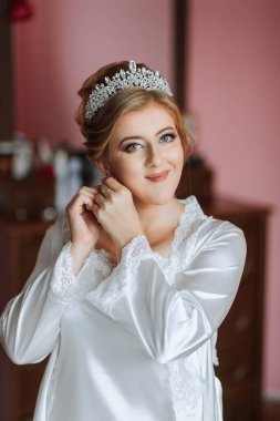 Bir kadın taç takıyor ve saçını düzeltiyor. Gülümsüyor ve özel bir durum için hazırlanıyor.