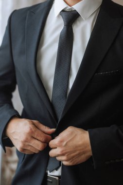 Takım elbiseli bir adam kravatını düzeltiyor. Formalite ve profesyonellik kavramı. Çünkü adam takım elbise ve kravat giymiş.