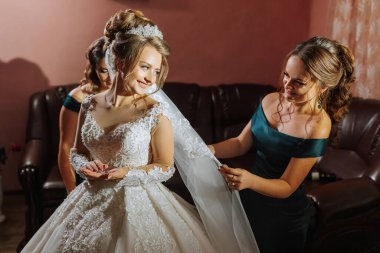 Bir gelin düğün için hazırlanıyor ve nedimesi duvağı için ona yardım ediyor.