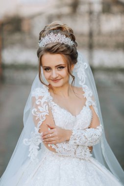 Beyaz gelinlik ve taç giyen bir kadın. Bir çitin önünde duruyor.