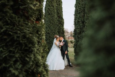 Bir gelin ve damat bir sıra ağacın önünde duruyor. Gelin beyaz bir elbise giyiyor ve damat bir takım elbise giyiyor. El ele tutuşup birbirlerine bakıyorlar. Sahne çok romantik.