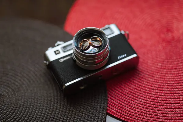 stock image A camera with a black body and a silver lens sits on a red and black table. The camera is a Canon brand and has a black and silver color scheme