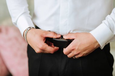 Bir adam kemerini ayarlıyor. Formalite kavramı ve detaylara dikkat
