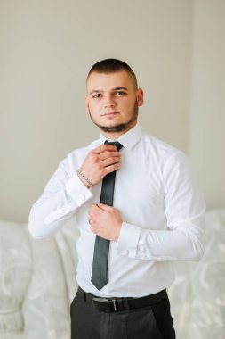 Beyaz gömlekli ve siyah kravatlı bir adam kravatını bağlamaya hazırlanıyor. Formalite ve profesyonellik kavramı. Çünkü adam takım elbise ve kravat giymiş.