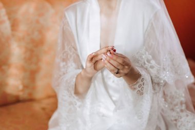 Yüzük tutan beyaz cüppeli bir kadın. İmajın romantik ve samimi bir havası var. Kadın alyans takıyor.