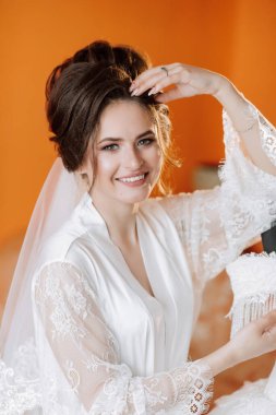 Beyaz bornoz ve duvak takan bir kadın var. Gülümsüyor ve kameraya bakıyor.