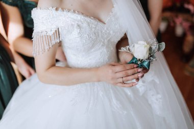 Bir gelin beyaz bir elbise giyiyor ve elinde beyaz bir gül tutuyor. Zarafet ve romantizm kavramı. Gelin güzel bir gelinlik giyip elinde bir çiçek tutuyor.