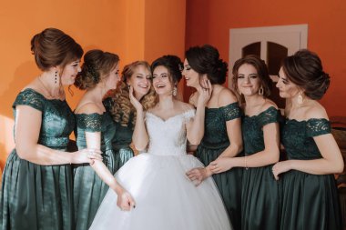 Bir grup kadın bir resim için poz veriyor, içlerinden biri beyaz bir elbise giyiyor. Sahne mutlu ve kutlama dolu, çünkü kadınlar gülümsüyor ve birbirlerinin arkadaşlığından zevk alıyorlar.