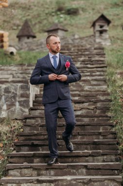 Takım elbiseli bir adam merdivenleri çıkıyor. O, yakasına bir kravat ve pembe bir çiçek takıyor. Adam takım elbise ve kravat giydiği için resmiyet ve zarafet kavramı.
