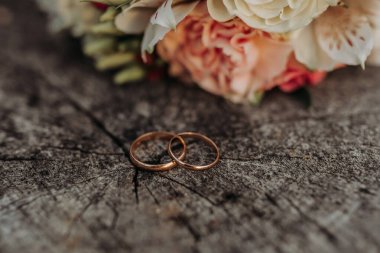 İki alyans tahta bir yüzeye yerleştirilir. Yüzükler altın ve yeni alınmış gibi görünüyor. Aşk ve bağlılık kavramı, yüzükler genellikle bir düğün töreninde takas edilir.