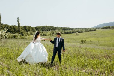 Bir gelin ve damat düğün günlerinde bir tarlada yürüyorlar. Gelin beyaz bir elbise giyiyor ve damat bir takım elbise giyiyor. Sahne mutlu ve romantik.