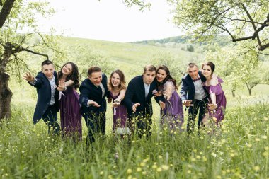 Tarlada fotoğraf çektirmek için poz veren bir grup insan. Sahne mutlu ve dostane.