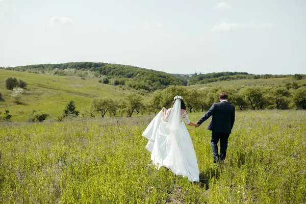 Bir gelin ve damat düğün günlerinde bir tarlada yürüyorlar. Gelin beyaz bir elbise giyiyor ve damat bir takım elbise giyiyor. Alan yemyeşil ve yemyeşil.