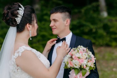 Gelin ve damat bir tarlada duruyorlar, gelin beyaz bir elbise giyiyor ve damat siyah bir takım elbise giyiyor. Gelin bakarken damat kravatını düzeltiyor. Arka planda