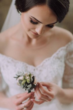 Bir gelin elinde bir çiçek tutuyor. Çiçek yeşil ve beyazdır. Gelin beyaz bir elbise ve duvak takıyor. Mutluluk ve kutlama kavramı