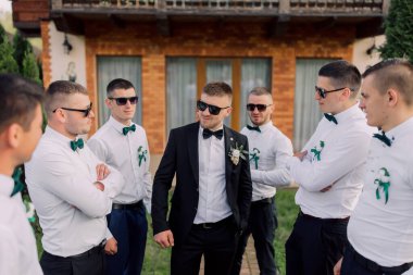 Takım elbiseli ve kravatlı bir grup adam bir çemberin içinde duruyorlar, alyans takan bir adamla.