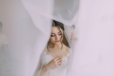 Bir gelin düğünü için hazırlanıyor ve bir perdenin arkasından dışarı bakıyor. Beyaz bir elbise giyiyor ve saçları topuz şeklinde. Sahne penceresi olan bir odada geçiyor.