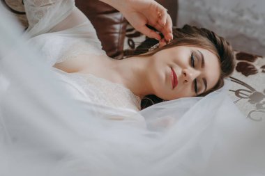 Beyaz çarşaflı ve peçeli bir kadın yatakta yatıyor. Beyaz bir elbise giyiyor ve saçları topuz şeklinde. Zarafet ve incelik kavramı