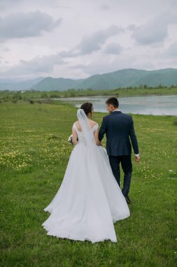 Bir gelin ve damat bir tarlada birlikte yürüyorlar. Gelin beyaz bir elbise giyiyor ve damat mavi bir takım elbise giyiyor. Huzurlu ve huzurlu bir sahne.