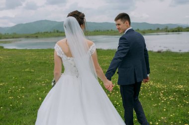 Bir gelin ve damat bir tarlada birlikte yürüyorlar. Gelin beyaz bir elbise giyiyor ve damat mavi bir takım elbise giyiyor. Sahne huzurlu ve romantik.