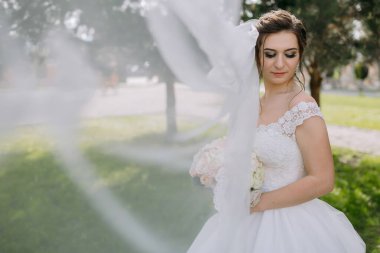 Beyaz elbiseli bir kadın tarlada dikiliyor. Yüzünde duvak var. Elinde bir buket çiçek tutuyor.