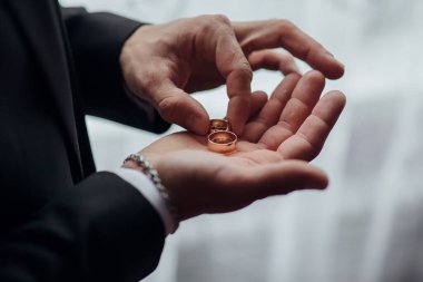 Bir adam elinde iki altın alyans tutuyor. Yüzükler parmaklarına takıldı ve o bir takım elbise giyiyor. Aşk ve bağlılık kavramı, adamın ortağına evlenme teklif etmek üzere olduğu gibi.