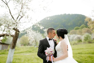 Bir gelin ve damat arkalarında bir ağaçla bir tarlada duruyorlar. Gelin beyaz bir elbise giyiyor ve damat siyah bir takım elbise giyiyor. El ele tutuşup birbirlerinin gözlerine bakıyorlar.