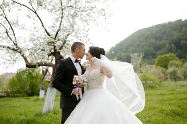 Bir gelin ve damat arkalarında bir ağaçla bir tarlada duruyorlar. Gelin beyaz bir elbise giyiyor ve damat bir takım elbise giyiyor. El ele tutuşup kameraya gülümsüyorlar.