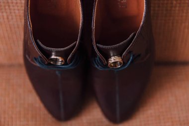 Üzerinde altın yüzük olan bir çift ayakkabı.