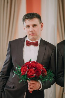 Elinde bir buket kırmızı gül tutan takım elbiseli ve kravatlı bir adam. Zarafet ve entelektüellik kavramı. Çünkü adam resmi giyinmiş ve güller aşkın ve romantizmin sembolü.