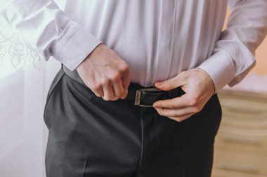 Bir adam kemerini ayarlıyor. Formalite kavramı ve detaylara dikkat