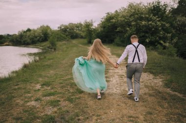 Bir çift gölün yakınındaki bir tarlada birlikte koşuyor. Adam beyaz gömlek ve siyah pantolon askısı giyiyor. Kadın yeşil bir elbise giyiyor.