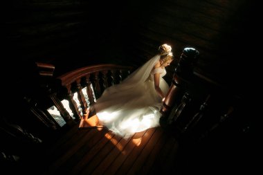 Gelinlikle merdivenlerden inen bir gelin var. İmajın romantik ve zarif bir havası var.