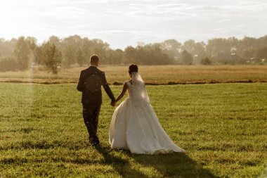Bir gelin ve damat düğün günlerinde bir tarlada yürüyorlar. Gelin beyaz bir elbise giyiyor ve damat bir takım elbise giyiyor. Çift el ele tutuşuyor ve anın tadını çıkarıyor.