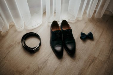 Bir çift siyah ayakkabı ve bir kemer ahşap bir zeminde. Ayakkabılar düzgünce yerleştirilmiş ve kemer onların yanına yerleştirilmiş. Ayakkabılar gibi zarafet ve entelektüellik kavramı.