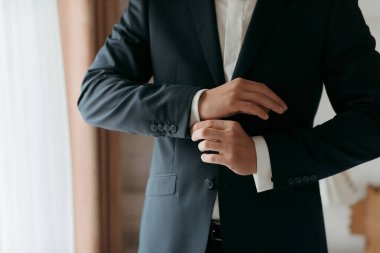 Takım elbiseli bir adam ceketini ve gömleğini düzeltiyor. Formalite ve profesyonellik kavramı. Çünkü adam takım elbise ve kravat giymiş.