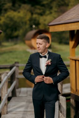 Takım elbiseli bir adam köprüde duruyor, kravatını düzeltiyor. Sahnenin resmi ve zarif bir havası var. Smokin giymiş bir adam ve köprü altında fevkalade bir zemin hazırlıyor.