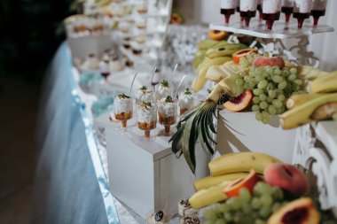 Muz ve üzüm de dahil olmak üzere çeşitli tatlı ve meyvelerle dolu bir masa. Masa bir parti ya da toplanma için hazır.