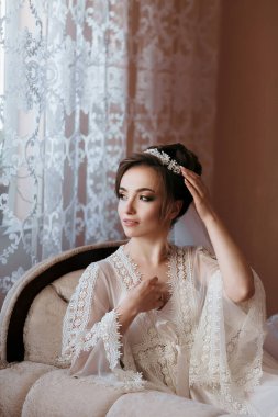 Beyaz önlük ve saç bandı takmış bir kadın sandalyede oturuyor. O, yüzünde bir gülümsemeyle kameraya bakıyor. Zarafet ve incelik kavramı