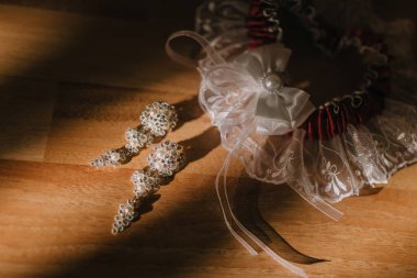 Bir çift küpe ve beyaz dantel bir yay ahşap bir masada sergilenir. Küpeler incilerden yapılmış ve fiyonk ile birlikte masaya konuyor. Zarafet ve incelik kavramı