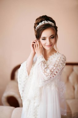 Beyaz elbiseli bir kadın düğüne hazırlanıyor. Dantelli bir bluz ve saç bandı takıyor.