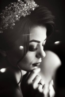 İnci bantlı bir kadın kameraya bakıyor. Kadının bakışları çerçevenin ötesindeki bir şeye odaklanmış gibi görünürken, görüntüde tuhaf ve gizemli bir his var. Siyahın kullanımı