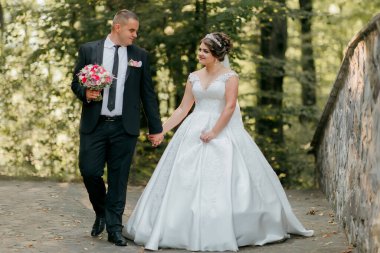 Bir gelin ve damat ormanda bir patikada yürüyorlar. Gelin beyaz bir elbise giyiyor ve damat bir takım elbise giyiyor. El ele tutuşuyorlar ve mutlu ve aşık görünüyorlar.