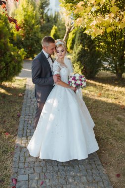 Gelin ve damat tuğla bir geçitte duruyorlar, gelin elinde buketle