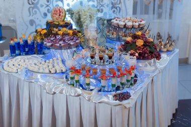 Muhtelif tatlı ve içeceklerle dolu bir masa. Kekler, meyveler ve pasta da dahil.