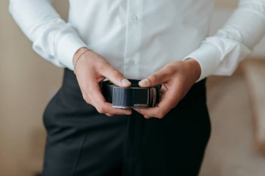 Bir adam kemer takıyor ve elinde kamera tutuyor. Profesyonellik kavramı ve detaylara dikkat, adam takım elbise ve kravat giymiş ve kamerasına odaklanmış.